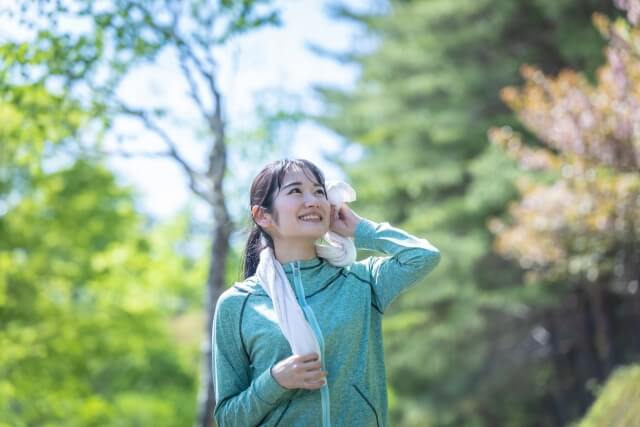 自然の中で運動後に汗をふく女性
